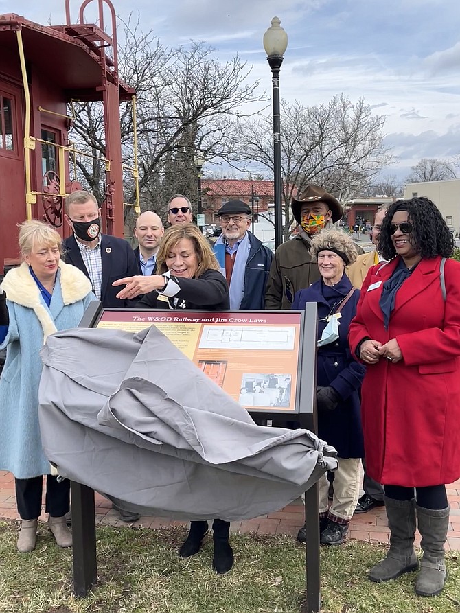 Cate Magennis Wyatt, Loudoun County board chairperson NOVA Parks unveils  NOVA Park's new interpretive sign panel, "The W&OD Railway and Jim Crow Law." The W&OD Trail runs through the Town of Herndon beside the iconic Washington & Old Dominion  Red Caboose.