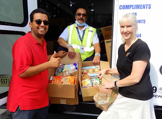 At a previous Stuff the Bus event outside Centreville Regional Library, (from left) Yousef Alrajhi with Volunteer Fairfax, bus driver Saeid Khalighi and WFCM’S Sarah Barton with some of donated food.