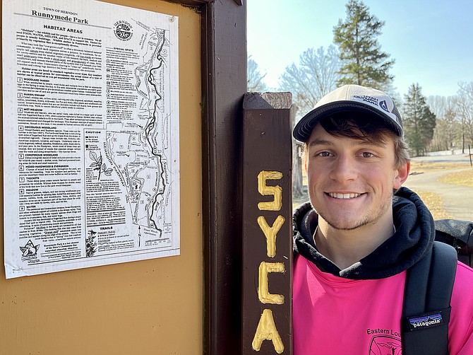 Eagle Scout candidate Ryan Lindley of BSA Troop 2970 stands beside a Town of Herndon Runnymede Park map noting its trails. In his hand is a new trail sign, part of his Eagle Scout project.