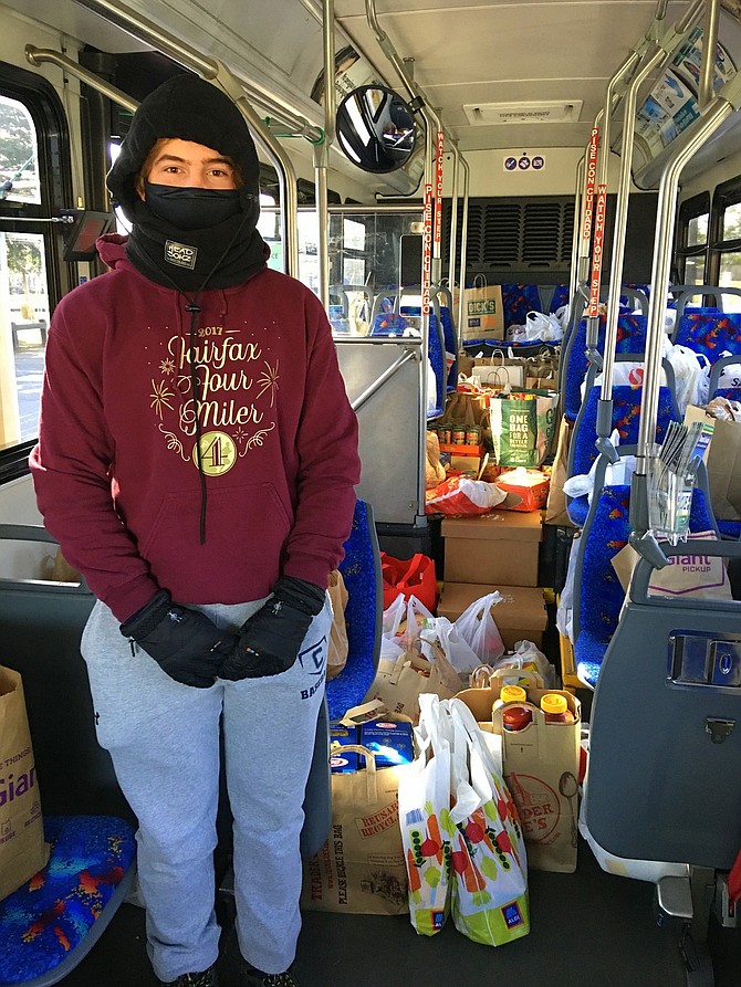 Volunteer Adam Taylor stands inside a CUE bus filled with food that residents brought to Fairfax City’s Van Dyck Park to contribute to Food for Others during a previous Stuff the Bus event.