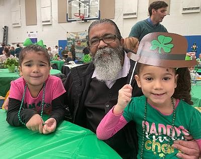 Jose Canales, center, with granddaughters Angelic and Angelika Guadalupe enjoy the Irish Hooley March 13 at the Basilica School of Saint Mary.