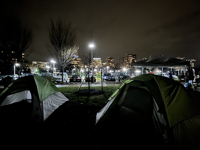 The skyline of Reston Town Center gleams outside their tent doors.