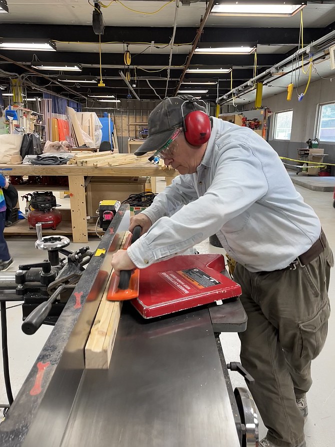 Safety goggles and ear protectors are in place as Randy Hill prepares a board on the jointer.