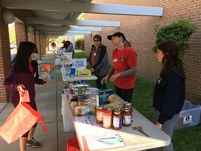 Andrea Wilkinson (in red), the local event coordinator for Food For Neighbors, led volunteers in sorting food that will support students in six area schools: Walt Whitman Middle School, West Potomac High School, Bryant High School, Sandburg Middle School, Mount Vernon High School, and Quander Road School.