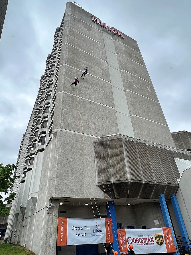 Alexandria resident John Bordner, on right, and Christy Keder of KW Metro Center rappel down the side of the Crystal City Hilton May 6 as part of the Over the Edge fundraiser for New Hope Housing.