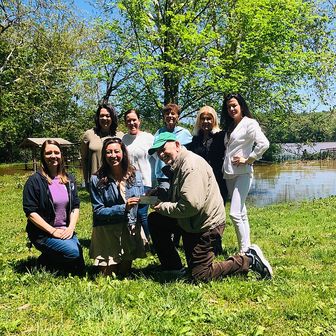 Stephanie Anderson, member of the Women's Club Philanthropy Group, hands a check to Hugh Morrow III, president of Friends of Riverbend Park. (Left to right) Kylie Starck, June Kelly, Grace McDaniel, Diane Lahey, Teresa Yurt, and Silvie Stankova