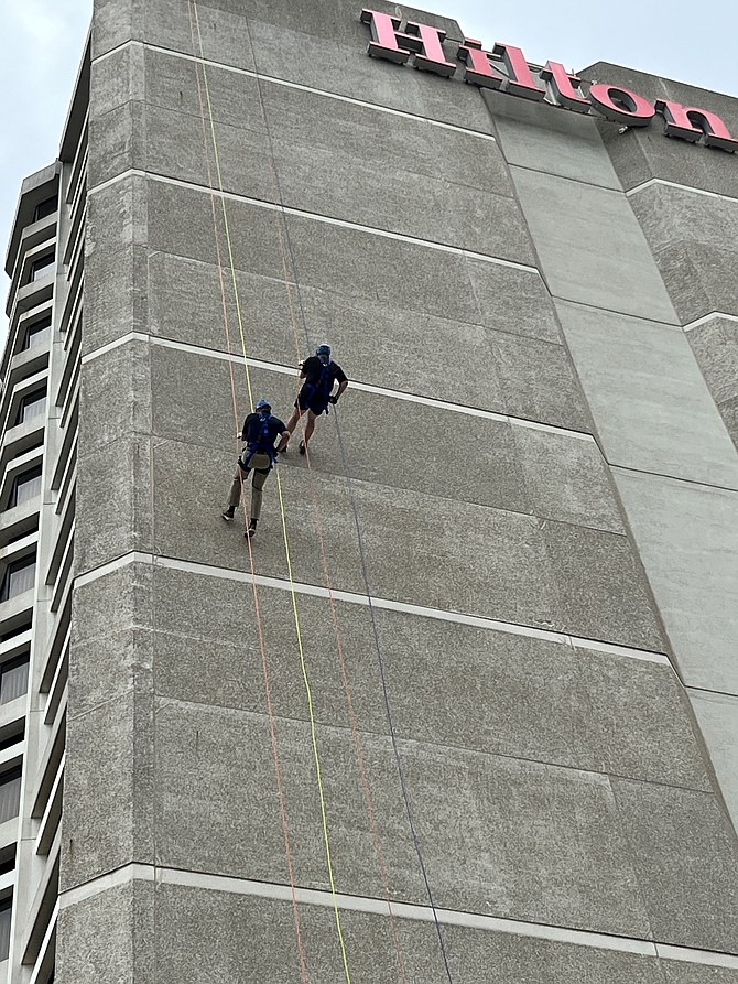 Arlington County Board member Matt de Ferranti, on right, rappels down the side of the Crystal City Hilton with Fairfax County Board of Supervisors chair Jeff McKay May 5 in support of New Hope Housing.