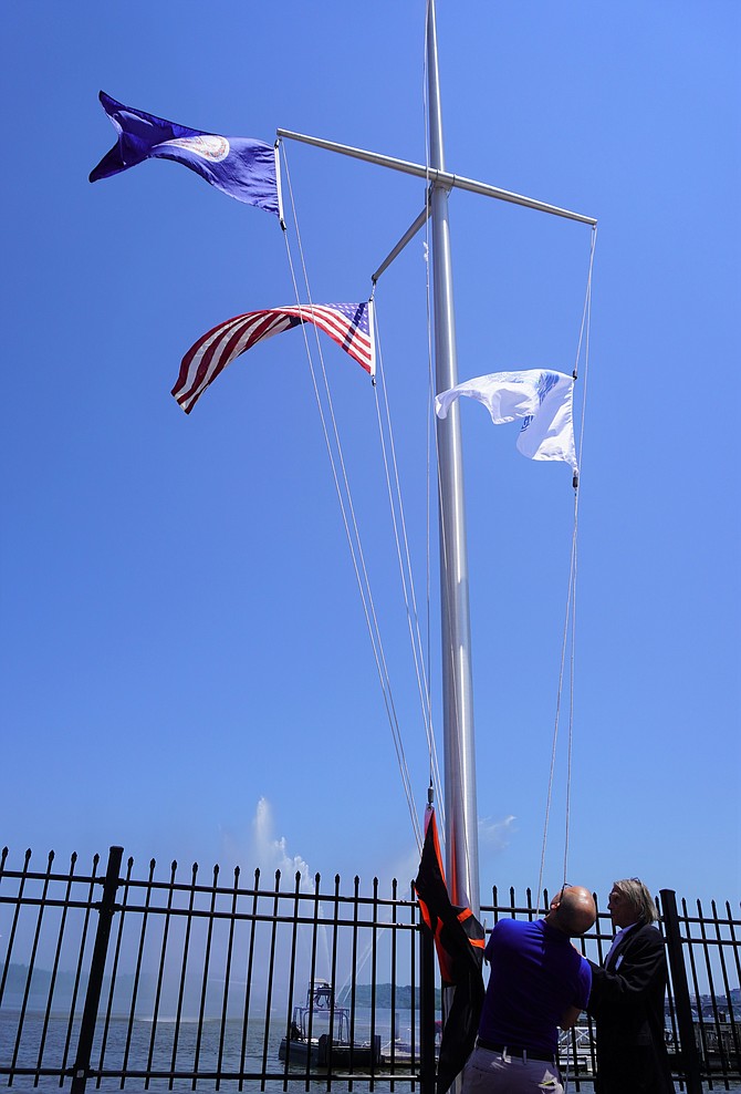 Mayor Justin Wilson, left, assists Richard Lloyd of the Old Dominion Boat Club in raising the City of Alexandria flag as part of the organization’s 142nd flag raising ceremony May 22 in Old Town.