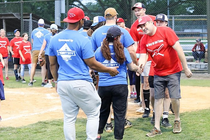 Bill Blackburn, right, leads the Del Ray Business Association softball team in shaking hands with members of the Old Town Business Association team following the May 26 game at Simpson Park.