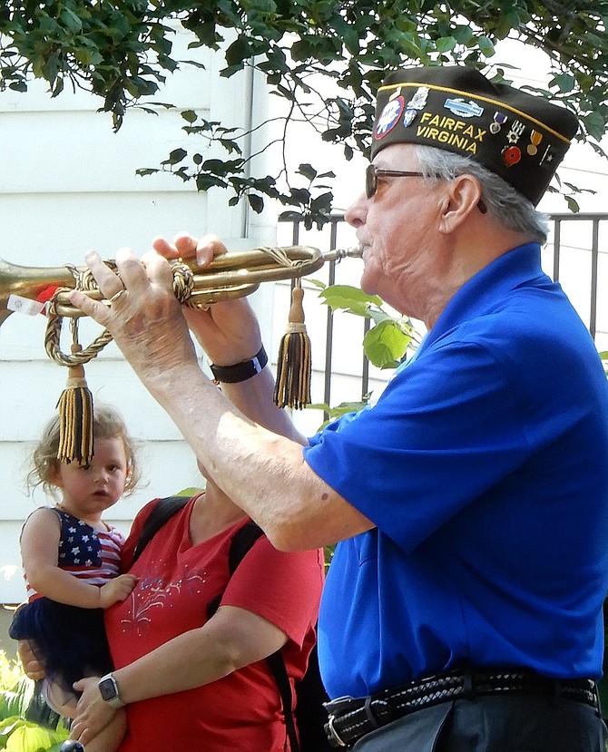 A little girl listens intently while the VFW’s Hank Roeder plays “Taps.”