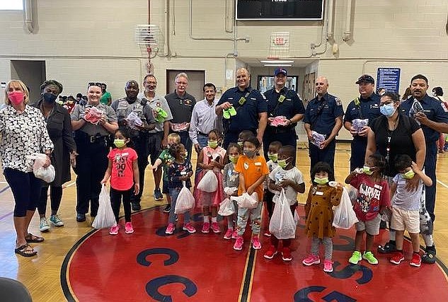 Firefighters and volunteers gather for a photo with children at the Firefighters and Friends shoe distribution June 2 at Gum Springs Community Center.