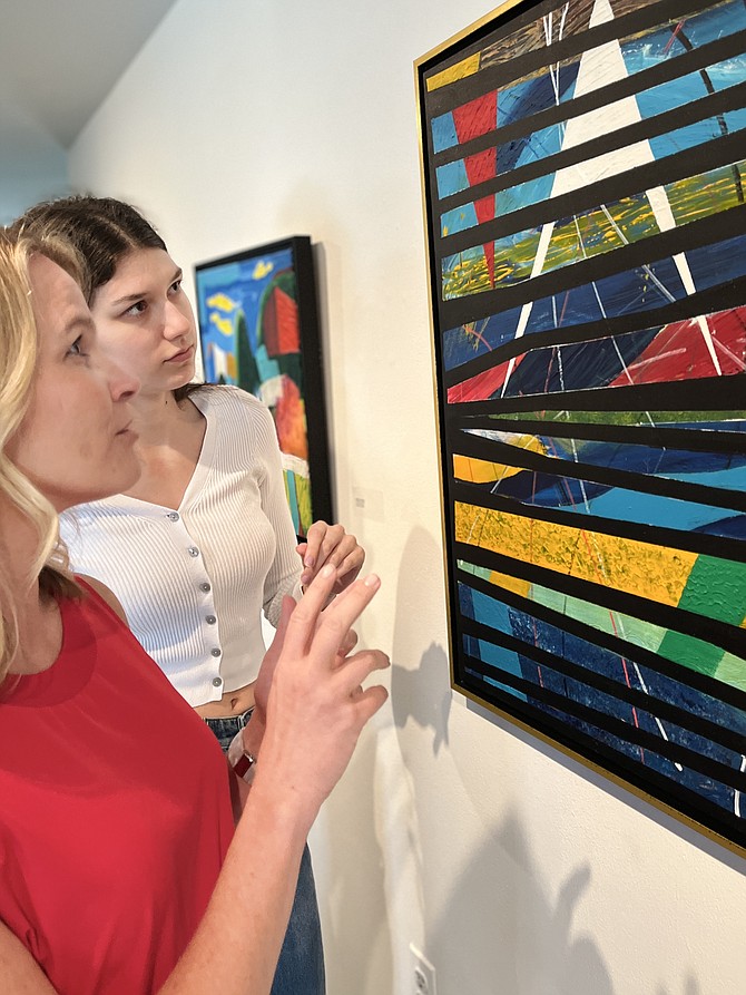From left, Eryn Lampe, development manager at MPA, and Manuela Salgado, MPA intern and NVCC student, discuss "Fusion" by Ricardo Pizarro, an acrylic on canvas painting.