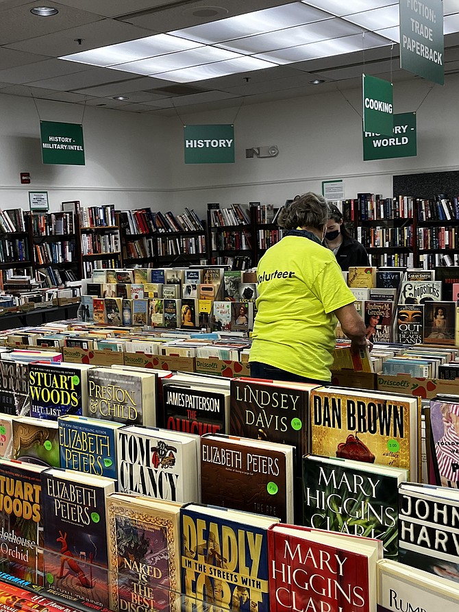 During the Spring Big Sale in 2022 at the Reston Regional Library, a volunteer takes care of the shelves. Bestseller hardcover books and other goods were available for as little as a few dollars each.
