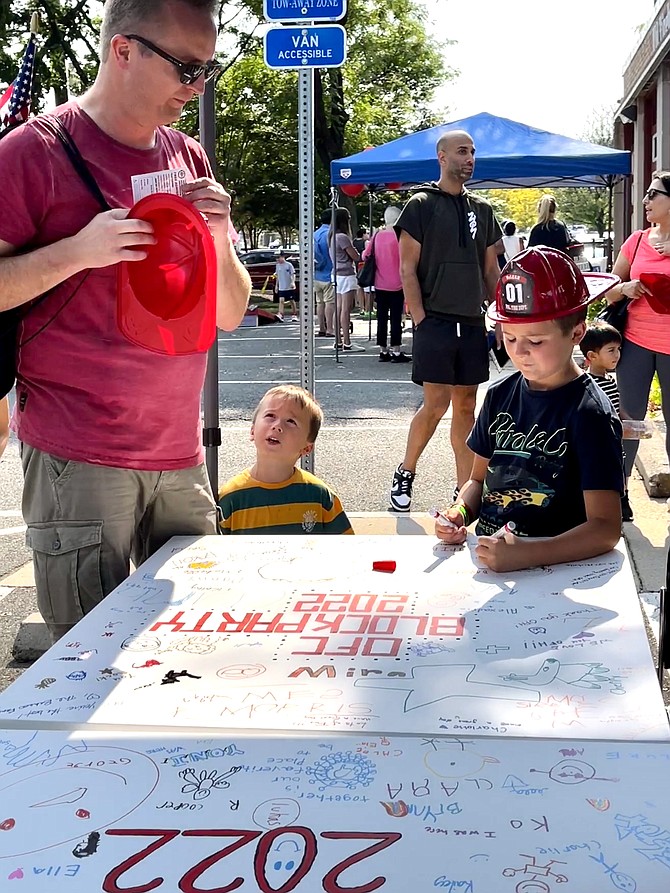 Bastiaan, 8, Sander, 4, and their dad, newly relocated to McLean 4 weeks ago, take in the Old Firehouse block party to mark 32 years of the Old Firehouse Center serving the Greater McLean community.