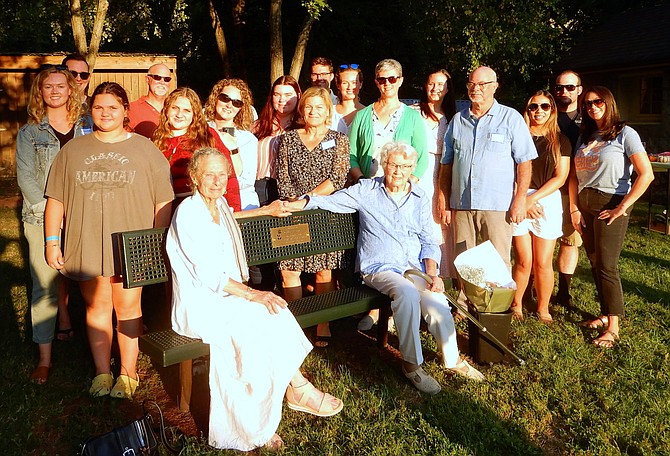 From left, Peggy Bier and Dolores Rooney sit together on the bench, with Rooney’s family gathered around them.