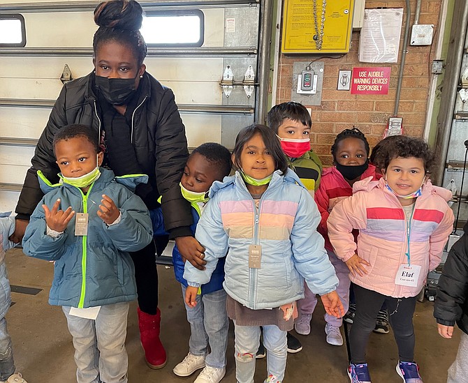 A volunteer helps Gum Springs Head Start children show off their new coats at the Firefighters and Friends coat distribution Oct. 20 at Penn Daw Fire Station 11.