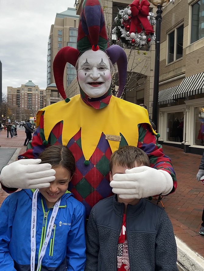 Steve, one of the award-winning, sweet and crazy Jokesters, plays with parade-goers Erin Martonik, 11, and her brother Ryan, 8, of Reston. This is their fourth time attending a Reston Holiday Parade.
