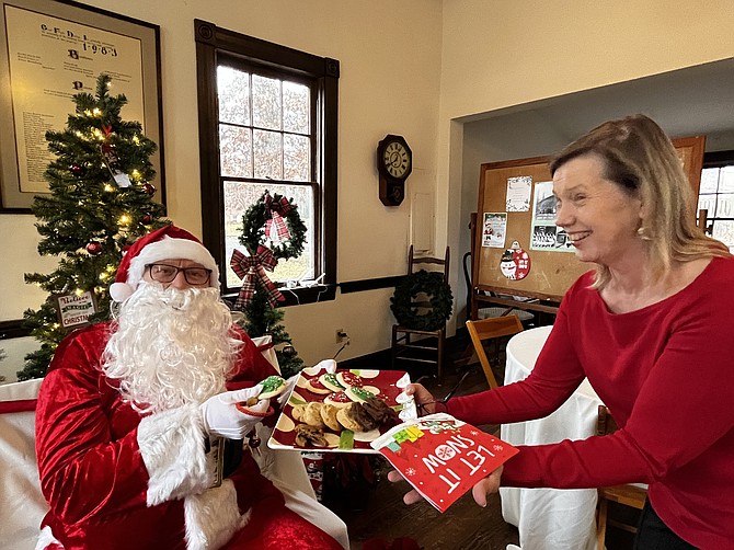 Julie Maher, executive director of the Great Falls Grange Foundation, offers Santa some holiday cookies.