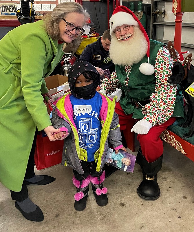 Fairfax County School Board member Karen Corbett Sanders, left, with Lieutenant David Saunders as Santa Claus, volunteers during the Firefighters and Friends toy drive distribution Dec. 12 at Penn Daw Station 11.
