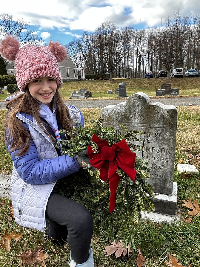 Maggie McIntosh, 10, lays a remembrance wreath at Chestnut Grove Cemetery in Herndon.