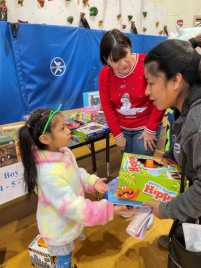 Volunteer Mindy Lyle, center, helps a family select toys during the Firefighters and Friends distribution day Dec. 17 at Samuel W. Tucker Elementary School.