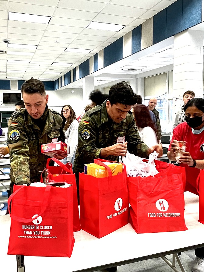 From left, Master Sergeant Manuel Pfaff and Captain Khalid Hashmi of the German Armed Forces Command United States and Canada serve beside local community members in Fairfax County to assist Food for Neighbors with its first distribution event of 2023.