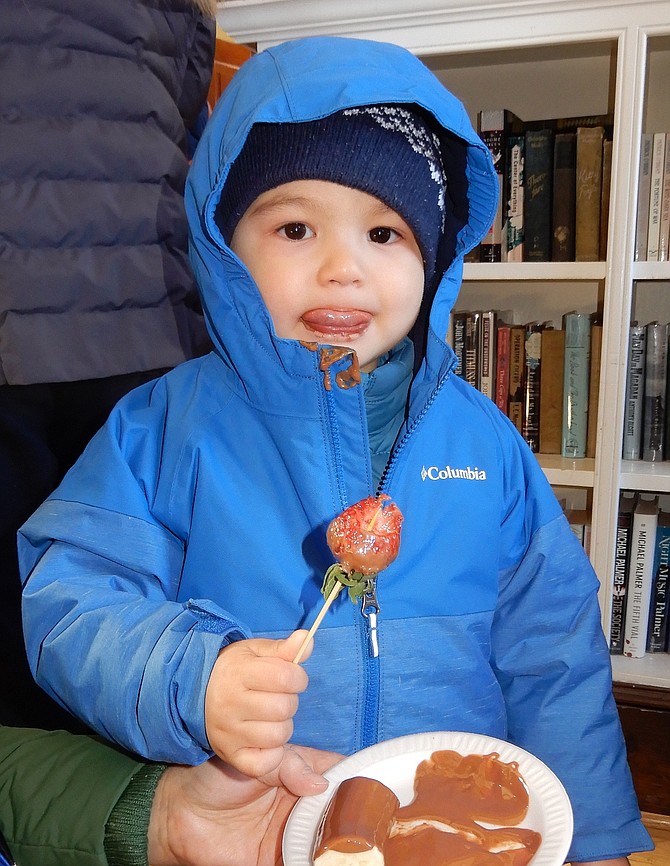 Leon Cui, 2-1/2, licks the chocolate off his lips from a strawberry that was covered in chocolate.