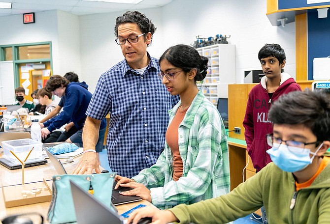 Carson MS technology education teacher Mark Bolt looks over students' work in the classroom.