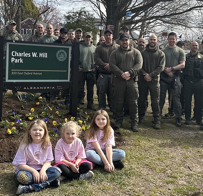 Members of the Alexandria Police Department Special Operations team join with Audrey, Eleanor and Laila Hill, seated, granddaughters of the late Corporal Charles Hill, at the annual park cleanup March 22 in Del Ray.