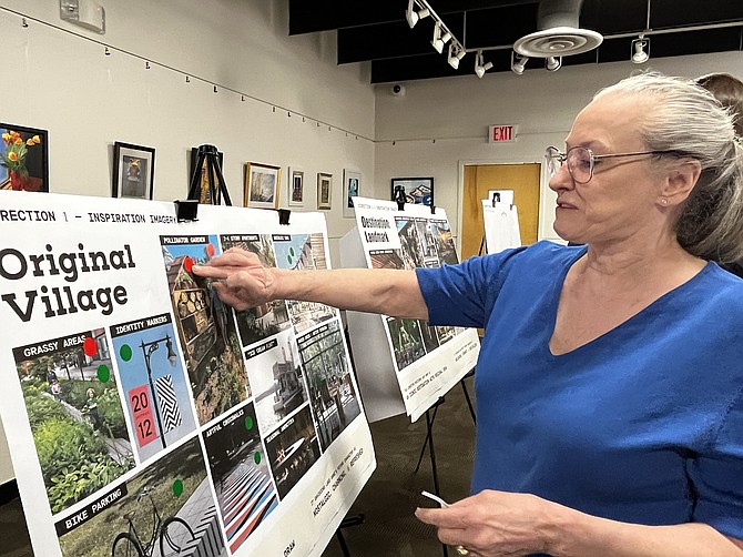 Martha Green, former LARCA president, puts one of her four red stickers indicating she does not prefer a pollinator garden in Direction 1 of the Lake Anne Visioning.