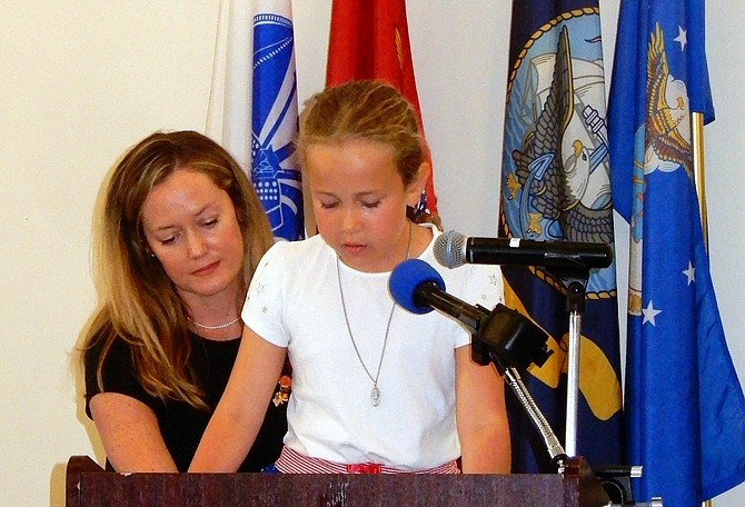 Fairfax City Councilmember Kate Doyle Feingold listens to Isabella Cosgrove, 8, read some names of fallen soldiers.
