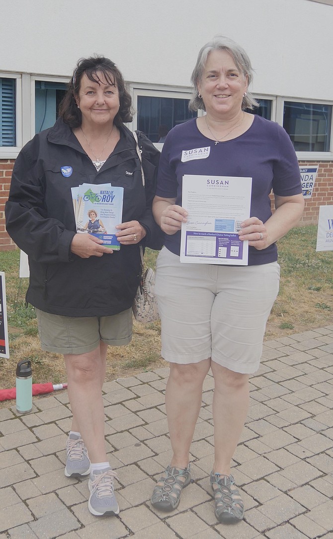 Poll greeters Angie Warren and Tierney Farrell stand outside Williamsburg Middle School door 4 on Tuesday, June 20 handing out campaign literature for their choice of County Board candidates. Warren says she supports Susan Cunningham because Cunningham will bring common sense and transparency to the Board, “and besides I’ve known her for a long time and she’s great.” Farrell supports Natalie Roy because “I feel she adds reason on the missing middle proposal.”