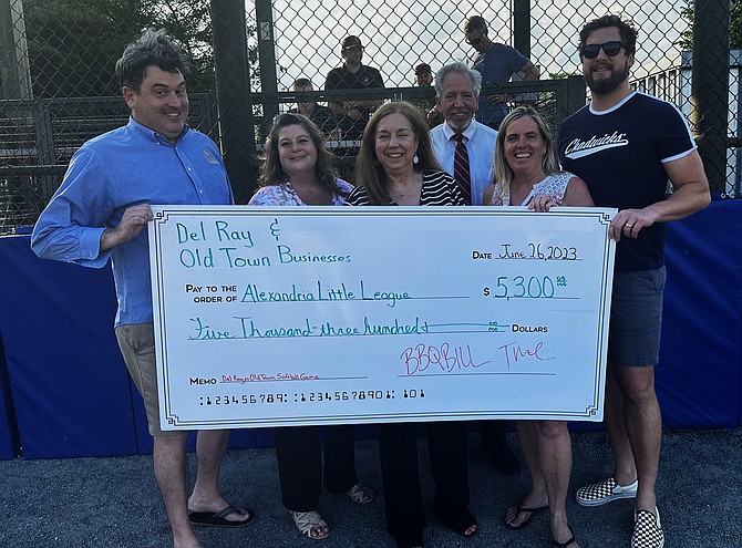 Alexandria Little League president Sherry Reilly, second from right, is presented a check for $5,300 from Del Ray and Old Town business leaders Bill Blackburn, Shannon Catlett, Gayle Reuter, Jason Yates and Trae Lamond June 26 at Simpson Field. The check represents proceeds from the annual Old Town vs. Del Ray softball game.