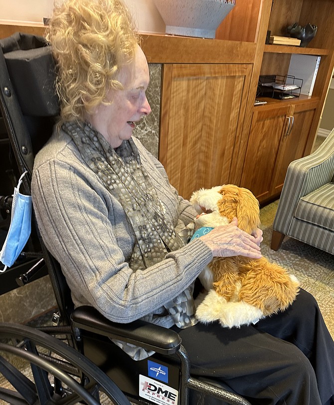 A resident at Goodwin House Alexandria interacts with a robotic companion pet.
