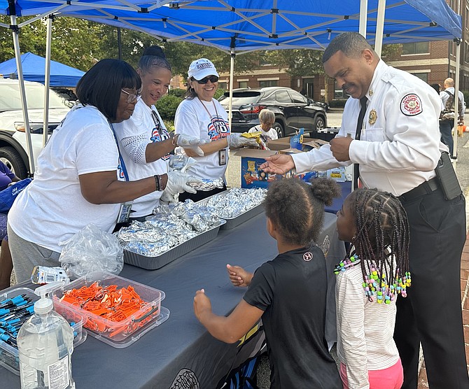 Fire Chief Corey Smedley, right, gets a hot dog during National Night Out Aug. 1 at Charles Houston Recreation Center.