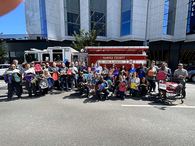 Volunteers from Capital One join Fairfax County firefighters displaying backpacks collected for the Firefighters and Friends to the Rescue back-to-school backpack drive Aug. 17 at Penn Daw Station 11.