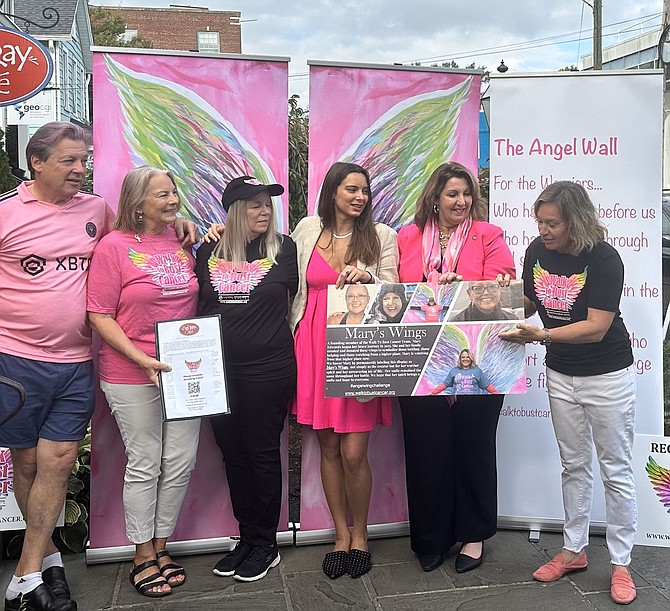 Martha Carucci, right, points to the poster describing “Mary’s Wings” as Laurent and Margaret Janowsky, Wendy Brown, Sandrine Janowsky and vice-Mayor Amy Jackson listen to the story Oct. 5 at the Walk to Bust Cancer kick off event at the Del Ray Café. The Walk will take place Oct. 15 at Fort Hunt Park.