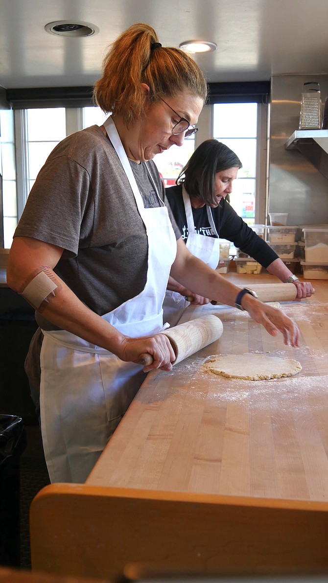 Heather Sheire (front) and Wendy MacCallum roll out pie dough that is full of butter, the secret ingredient.