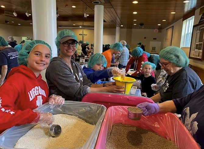 Volunteers (from left) Addie and her mom, Cathy Pollack, pack food packs at United Methodist Church for the U.S. Hunger project.
