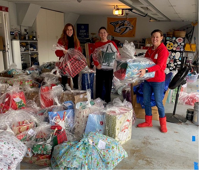 Great Falls volunteers Christie Shumadine, Avery Perez and Lissa Perez. 22 volunteers and elves dressed in red with bells and hats scurried to collect and wrap over a thousand gifts, stuff 100 stockings, and prepare gift cards to be delivered to 190 recipients.