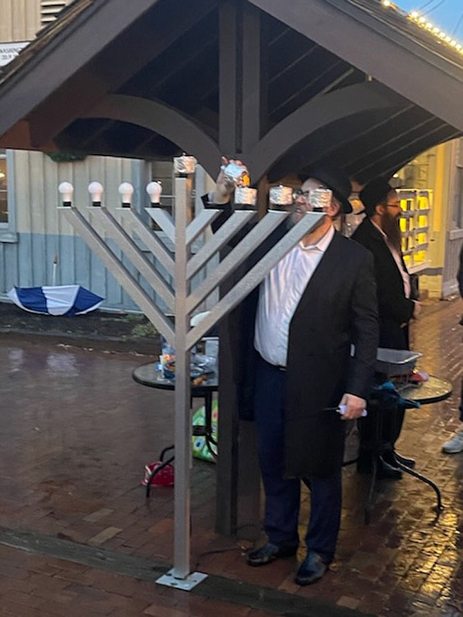Rabbi Ahron Fajnland of the Chabad Jewish Center of Reston- Herndon lights the oil pots on the menorah in the Town of Herndon. It serves as a symbol and message of the triumph of freedom over oppression, spirit over matter, light over darkness.