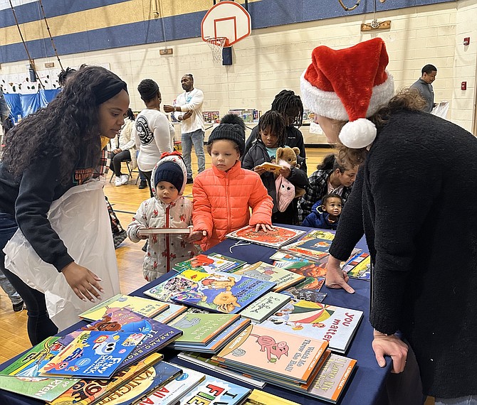 Volunteers help children select books as part of the Firefighters and Friends to the Rescue toy distribution Dec. 16 at Samuel Tucker Elementary School.