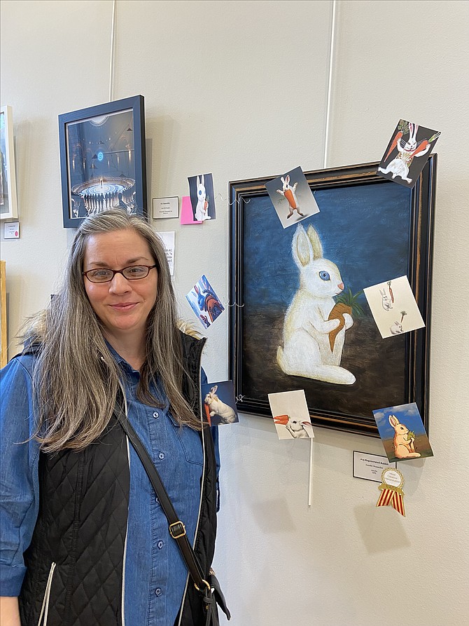 Jennifer Wessmiller with her painting, “Regenerated Rabbit,” embellished with images of AI’s interpretation of her work displayed at the AI & Us art exhibition.