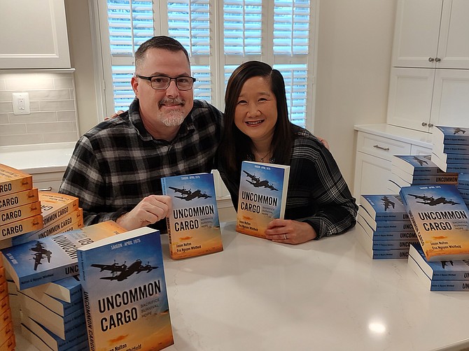 Authors Jason Nulton and Eva Nguyen Whitfield hold their book, “Uncommon Cargo: Sacrifice. Survival. Hope.” (2023), Deeds Publishing Athens