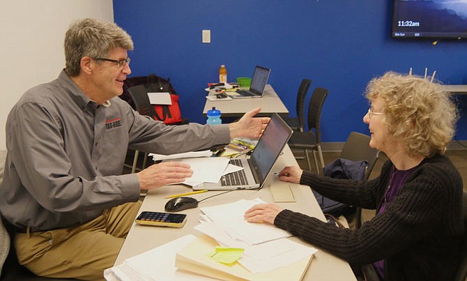 Tom Dwyer, AARP TaxAide volunteer with Marjorie Sauver who has come to get a free tax return prepared. Dwyer has been volunteering for 6-7 years “because it’s fun, you meet nice people and work with great people, too.”
