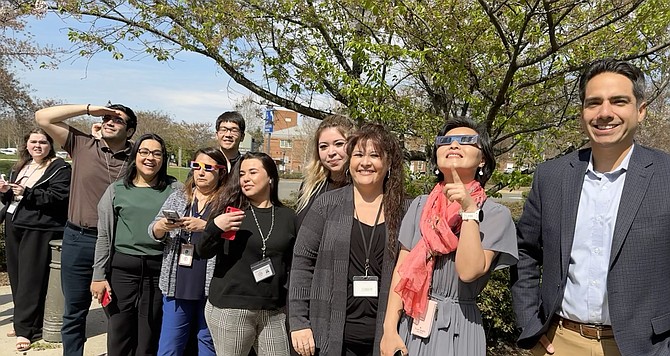 Minutes before the 3:20 p.m. moment of greatest coverage, the staff of Fairfax County Circuit Court Records Office gathered outside the courthouse for a chance to view the eclipse with office head, Chris Falcon (right).