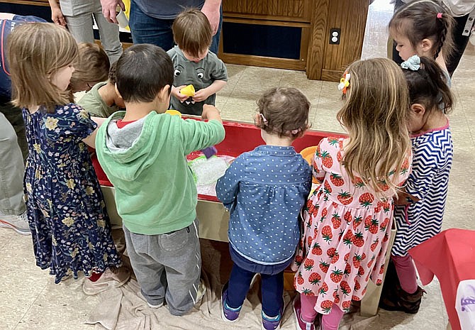 A group of preschool students learning about food and the kitchen wash dishes together