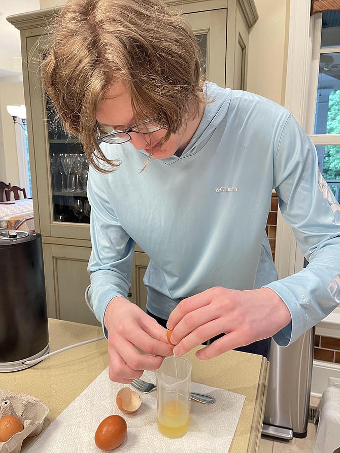 Lucas MacPhail is making a double batch of homemade fettuccine for the Alexandria Community Shelter for his Eagle scout project. He estimates this batch will feed six. First step is to break two eggs into a container, mix with fork and add 60 ml water. Then pour into pasta maker.