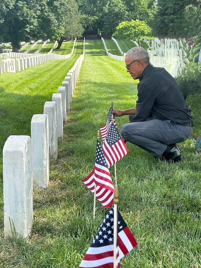 Former President Barack Obama places a flag at the grave of a fallen service member May 25 at Alexandria National Cemetery. Photo by Debbie Gray