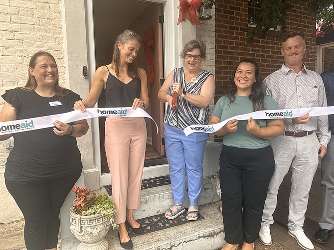 ALIVE! executive director Jennifer Ayers, center, cuts the ribbon to the ALIVE! House July 25 after renovations were completed on the transitional housing facility in Old Town.